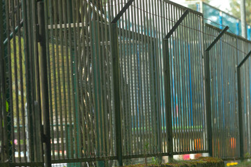 Obraz premium Tall security fence with angled tops, metal panels forming strong perimeter near public walkway, industrial aesthetic highlighting restriction and protection, suitable for surveillance, safety
