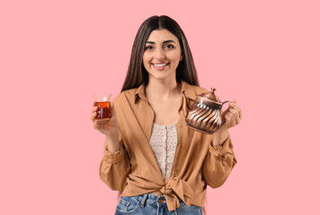 Young woman with Turkish tea and teapot on pink background