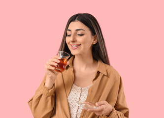 Naklejka premium Young woman with Turkish tea on pink background