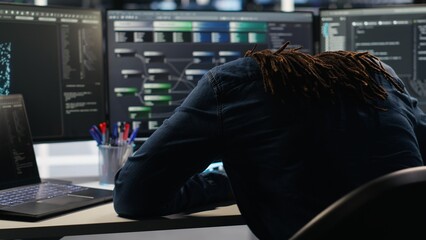 Angry server hub developer frustrated by slow data analytics AI generator. Annoyed data center worker punching desk, irked by glitching artificial intelligence program showing system metrics, camera B