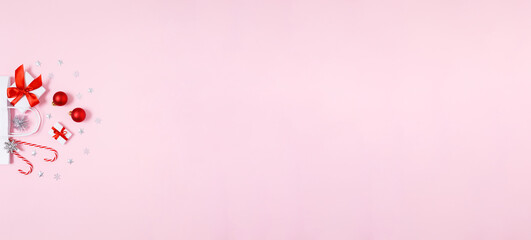 Minimal Christmas banner with white paper gift bag, presents, baubles and candy canes on soft pink copy space for holiday sales, social media ads and festive designs