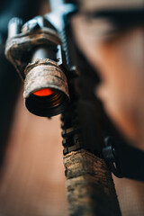 camouflaged rifle with a collimator sight