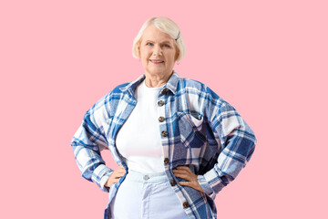 Stylish senior woman in plaid shirt on pink background