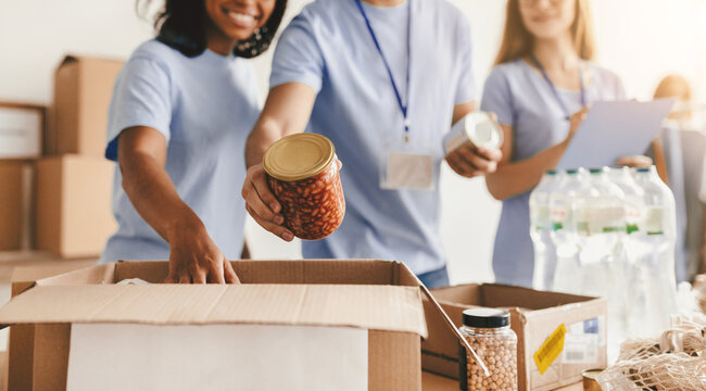 Group of volunteers working together to pack food items into boxes at a community center. They are organizing donations, showing teamwork and kindness.