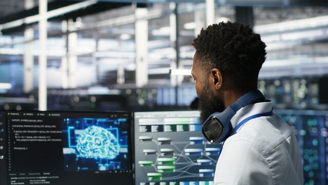 Data center system administrator using AI neural network models to configure hardware. Employee works on machine learning programming language in server room, optimizing system functionality, camera B - Powered by Adobe