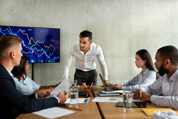 In a contemporary office, a young CEO speaks aggressively to his team about business failures. Employees appear upset, reflecting the tense atmosphere during the meeting.