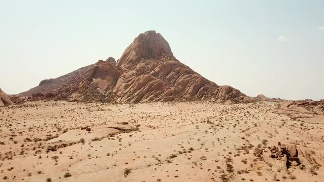 Aerial drone shot rising to the left with Spitzkoppe&rsquo;s granite mountain in view, capturing the rugged desert landscape of Namibia in smooth cinematic motion.