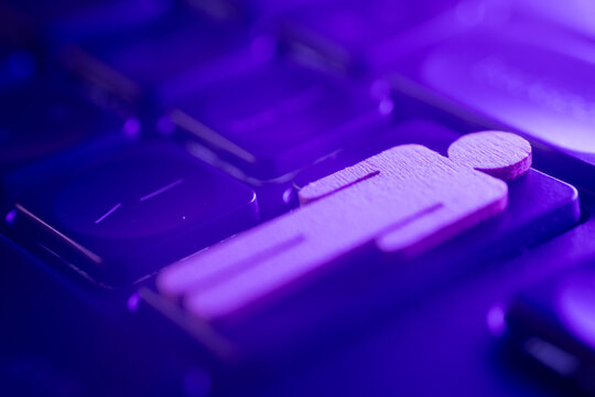 Wooden figure icon on a keyboard with vibrant purple lighting, symbolizing digital communication and user interaction in modern technology - Powered by Adobe