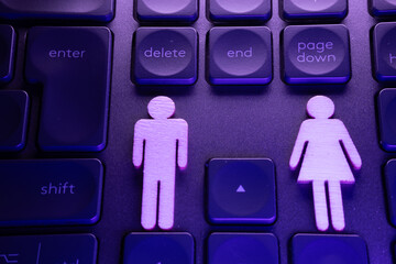 Wooden male and female symbols placed on a keyboard, highlighting gender representation in technology and digital communication
