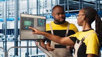System administrators in smart factory collecting and analyzing data. Coworkers doing brainstorming, using tracking software in industrial plant equipped with advanced sensors, camera A close up