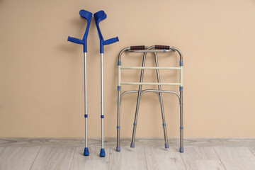 Medical walker with crutches near beige wall in room