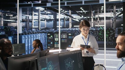 Server hub supervisor overseeing data scientist examining neural network algorithm on screen. Manager reviewing performance dashboards in artificial intelligence infrastructure environment, camera A