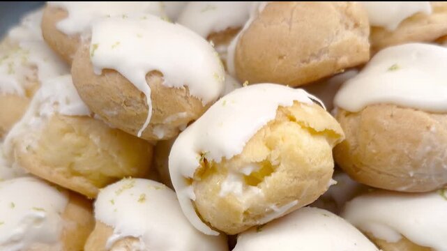 Several white chocolate Carolinas topped with lemon zest displayed in a Brazilian bakery showcase.
