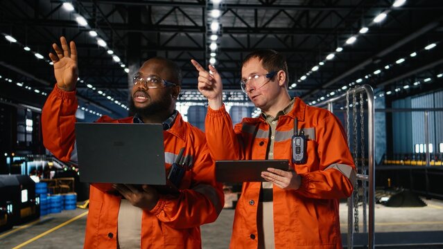 Colleagues use laptop and tablet to guide personnel during fabrication and production tasks, highlighting industrial labor and engineering. Operation of the manufacturing process.