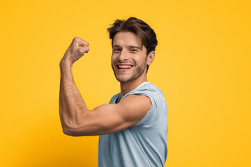 A young man stands proudly with his arm raised, flexing his muscles. He smiles brightly, showcasing his confidence against a vibrant yellow backdrop. The scene radiates positivity and strength.