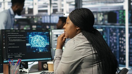 Data center staff member in office using AI deep learning algorithms to analyze datasets. African american woman in server room using artificial intelligence neural networks, camera B