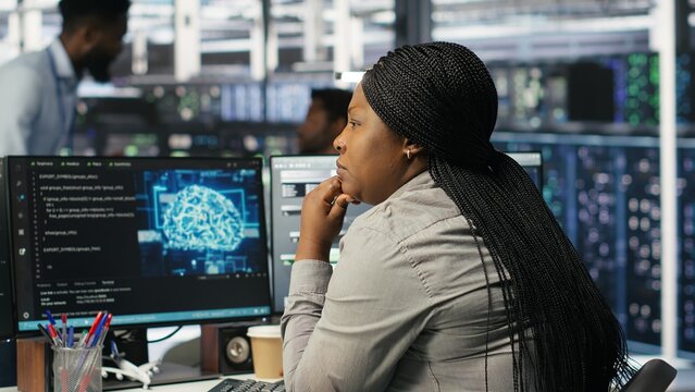 Data center staff member in office using AI deep learning algorithms to analyze datasets. African american woman in server room using artificial intelligence neural networks, camera B - Powered by Adobe