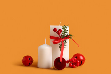 Beautiful Christmas composition with candles, bells and decorative berries on orange background