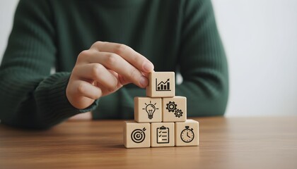 Hand stacking wooden blocks with business strategy icons representing planning growth and workflow for success isolated on a table