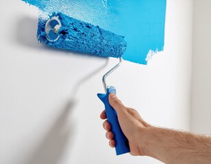 Close-up Of A Hand Holding A Blue Paint Roller Applying Bright Blue Paint To A White Wall Creating A Smooth Texture With Natural Lighting
