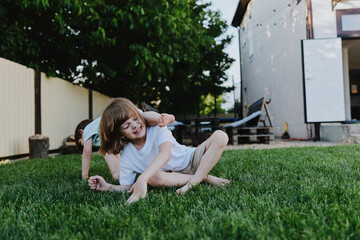Happy children playing on the grass, enjoying a sunny day in a backyard. Their laughter fills the air as they explore nature together.
