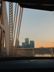 Fototapeta premium City skyline and steel bridge structure viewed through a car windshield at sunset