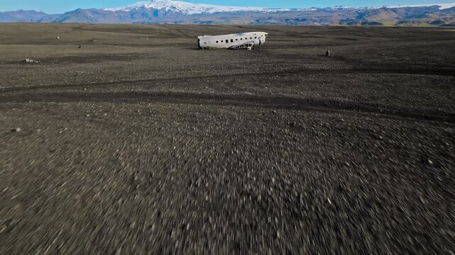 Solheimasandur DC-3 plane wreck Iceland drone aerial footage. 4K cinematic view shows abandoned fuselage resting on volcanic black sand desert.