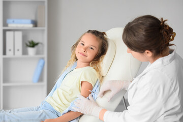 Fototapeta premium Female doctor vaccinating little girl in clinic