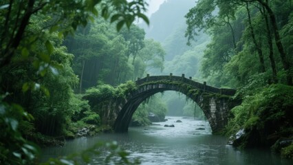 Stone arch bridge over a river in a lush green forest with misty atmosphere