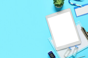 Blank tablet computer with doctor's supplies on blue background