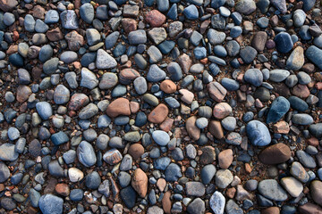 Natural outdoor background, colorful small rocks on wet pebble beach
