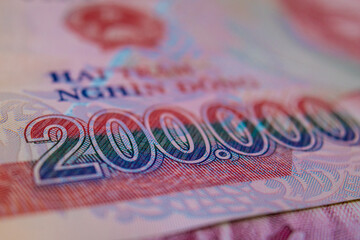 Close-up of a 200,000 Vietnamese Dong polymer banknote. The shot emphasizes the colorful denomination and intricate security patterns with a shallow depth of field and soft lighting. © RODWORKS