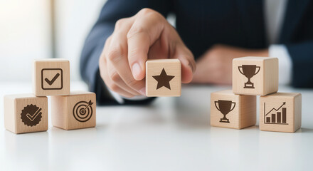 Key results achievement and marking a cube with a star using wooden cubes, symbolic icons, human hand, natural depth of field, soft blurred background, clean white desk