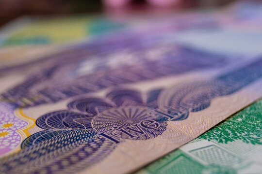 This macro shot captures the intricate details of a 25,000 Iraqi Dinar banknote. It features ornate guilloch&eacute; patterns, a vibrant purple and green palette, and crisp "TWENTY FIVE" English text.