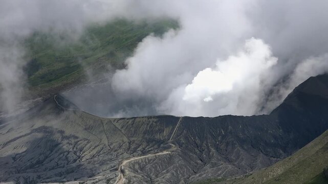Volumes of gases emitted from vent of active volcano. Seismic activity. Impressive landscape with Mount Bromo in Tengger Semeru National Park. East Java, Indonesia. Areal view. Camera stays still.