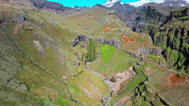Aerial view of mountain slopes near Mulagljufur Canyon. Drone footage showing rolling ridges, rocky cliffs, and green patches across the Icelandic highlands.