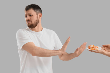 Young man rejecting female hands with shrimps on light background. Food Allergy Awareness Month