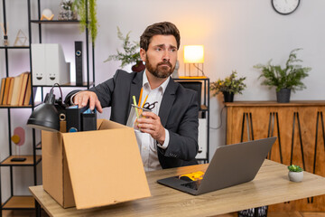 Middle-aged businessman at home office packs items carefully into box and glances around with nostalgia. Freelancer guy at table labels box closes notebook and smiles ready for next step in move soon.