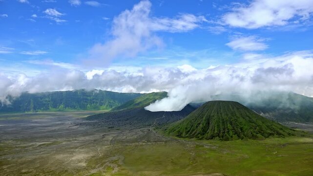 Volcanic eruption against blue sky. Volumes of thick smoke coming from crater of Mount Bromo, Tengger Semeru national park, East Java, Indonesia. Landscape with erupting volcano.