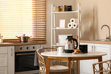 Interior of kitchen with electric kettle, tasty waffles and cup of tea on table