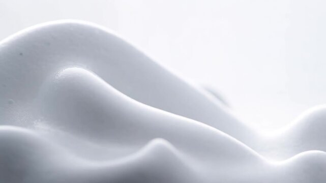 Abstract macro close up of soft white shaving foam with soft smooth wavy texture against a bright white
