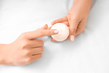 Young woman applying cream on bed, closeup
