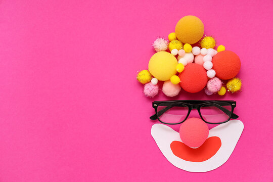 Funny clown's face made of glasses, colorful pompons and ball on pink background