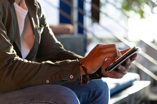 Tablet device sitting on bench beside metal staircase railing receiving taps in bright sunlight
