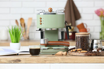 Modern coffee machine with glass cup of hot espresso and sweet cookies on counter in kitchen