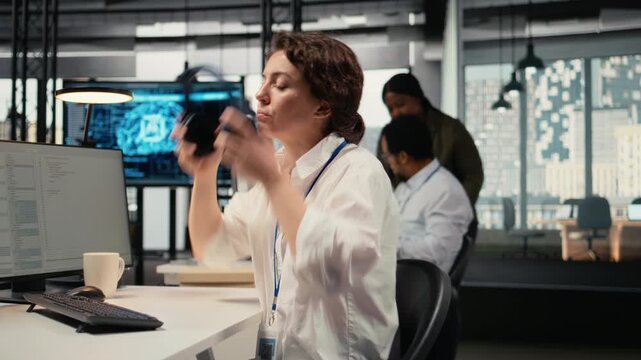 Stressed programmer in office listening music to relax while working with complex AI calculations. Fatigued IT employee putting audio headphones on, training deep learning systems, camera A