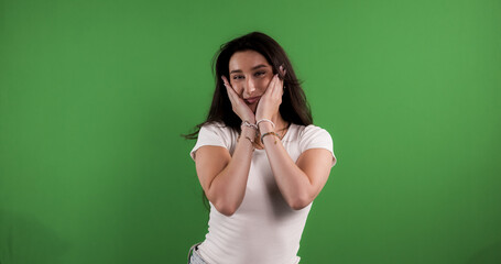 Studio portrait of a smiling brunette woman touching her on a green screen background. This image is suitable for beauty fashion and advertising campaigns.