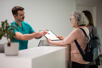 Fototapeta premium Medical professional handing clipboard for patient check-in
