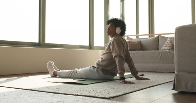 Mid adult man placing green mat on rug, performing backbend stretch promoting spine health at home