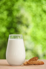 Jug of fresh milk and sweet cookies on beige table outdoors